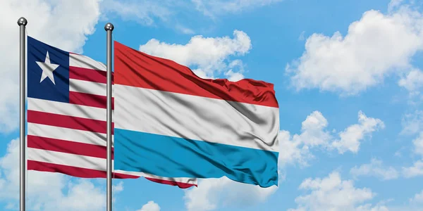 Ліберії і Люксембургу прапор розмахуючи в вітер проти білого хмарного синього неба разом. Концепція дипломатії, міжнародні відносини. — стокове фото