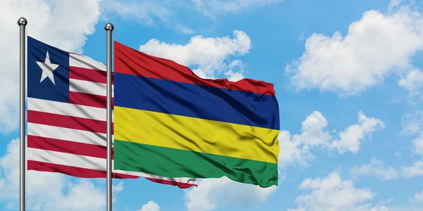 一緒に白い曇った青い空に対して風に手を振るリベリアとモーリシャスの旗。外交概念、国際関係. — ストック写真
