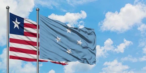 Bandera de Liberia y Micronesia ondeando en el viento contra el cielo azul nublado blanco juntos. Concepto diplomático, relaciones internacionales . — Foto de Stock