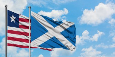 Liberya ve İskoçya bayrağı birlikte beyaz bulutlu mavi gökyüzüne karşı rüzgarda sallayarak. Diplomasi kavramı, uluslararası ilişkiler.