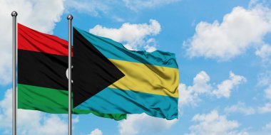 Libya ve Bahamalar bayrağı birlikte beyaz bulutlu mavi gökyüzüne karşı rüzgarda sallayarak. Diplomasi kavramı, uluslararası ilişkiler.