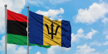 Libya ve Barbados bayrağı birlikte beyaz bulutlu mavi gökyüzüne karşı rüzgarsal sallayarak. Diplomasi kavramı, uluslararası ilişkiler.