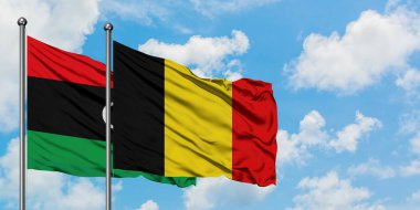 Libya ve Belçika bayrağı birlikte beyaz bulutlu mavi gökyüzüne karşı rüzgarsal sallayarak. Diplomasi kavramı, uluslararası ilişkiler.