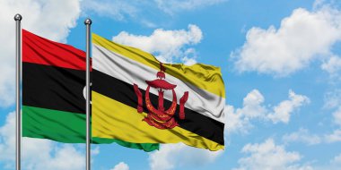 Libya ve Brunei bayrağı birlikte beyaz bulutlu mavi gökyüzüne karşı rüzgarda sallayarak. Diplomasi kavramı, uluslararası ilişkiler.