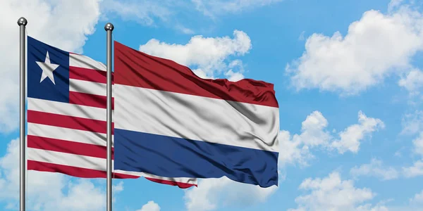 Liberya ve Hollanda bayrağı birlikte beyaz bulutlu mavi gökyüzüne karşı rüzgarda sallayarak. Diplomasi kavramı, uluslararası ilişkiler. — Stok fotoğraf