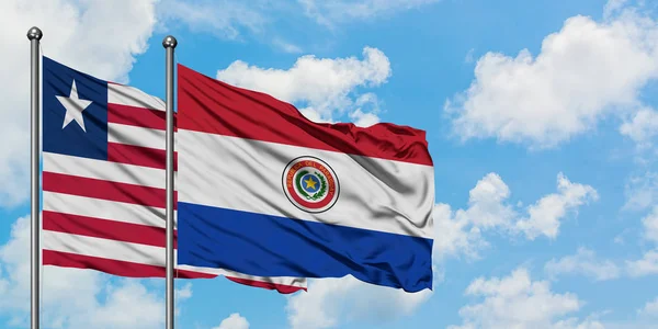 Ліберії і парагвайський прапор розмахуючи в вітру проти білого хмарного синього неба разом. Концепція дипломатії, міжнародні відносини. — стокове фото