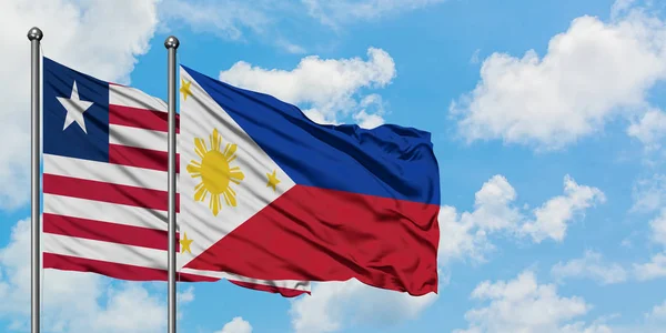 Libéria e Filipinas acenando ao vento contra o céu azul nublado branco juntos. Conceito de diplomacia, relações internacionais . — Fotografia de Stock