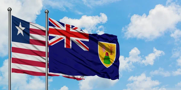 利比里亚和特克斯和凯科斯群岛国旗在风中飘扬，与白云蓝天相拥。外交概念、国际关系. — 图库照片