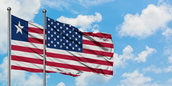 Liberia en de vlag van de Verenigde Staten zwaaien in de wind tegen witte bewolkte blauwe hemel samen. Diplomatie concept, internationale betrekkingen. — Stockfoto