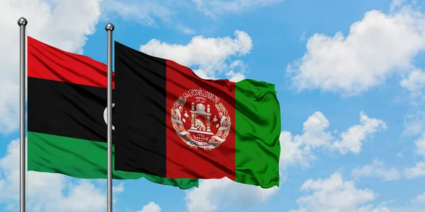 Bandera de Libia y Afganistán ondeando en el viento contra el cielo azul nublado blanco juntos. Concepto diplomático, relaciones internacionales . — Foto de Stock
