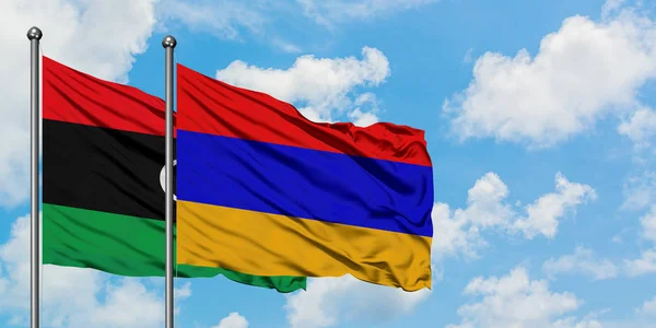 Bandera de Libia y Armenia ondeando en el viento contra el cielo azul nublado blanco juntos. Concepto diplomático, relaciones internacionales . — Foto de Stock