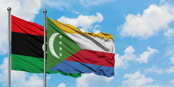 Bandera de Libia y Comoras ondeando en el viento contra el cielo azul nublado blanco juntos. Concepto diplomático, relaciones internacionales . — Foto de Stock