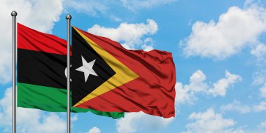 Libya ve Doğu Timor bayrağı birlikte beyaz bulutlu mavi gökyüzüne karşı rüzgarsal sallayarak. Diplomasi kavramı, uluslararası ilişkiler.