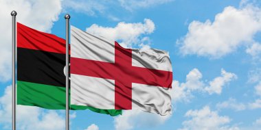 Libya ve İngiltere bayrağı birlikte beyaz bulutlu mavi gökyüzüne karşı rüzgarsal sallayarak. Diplomasi kavramı, uluslararası ilişkiler.