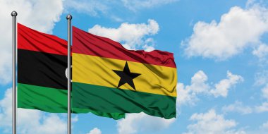 Libya ve Gana bayrağı birlikte beyaz bulutlu mavi gökyüzüne karşı rüzgarda sallayarak. Diplomasi kavramı, uluslararası ilişkiler.