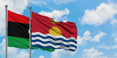 Libya ve Kiribati bayrağı birlikte beyaz bulutlu mavi gökyüzüne karşı rüzgarda sallayarak. Diplomasi kavramı, uluslararası ilişkiler.