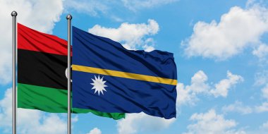 Libya ve Nauru bayrağı birlikte beyaz bulutlu mavi gökyüzüne karşı rüzgarda sallayarak. Diplomasi kavramı, uluslararası ilişkiler.