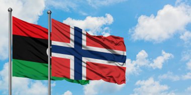 Libya ve Norveç bayrağı birlikte beyaz bulutlu mavi gökyüzüne karşı rüzgarsal sallayarak. Diplomasi kavramı, uluslararası ilişkiler.