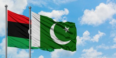 Libya ve Pakistan bayrağı birlikte beyaz bulutlu mavi gökyüzüne karşı rüzgarsal sallayarak. Diplomasi kavramı, uluslararası ilişkiler.