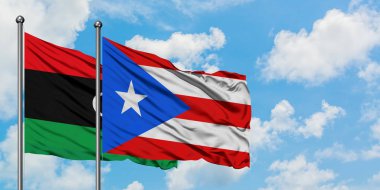 Libya ve Porto Riko bayrağı birlikte beyaz bulutlu mavi gökyüzüne karşı rüzgarda sallayarak. Diplomasi kavramı, uluslararası ilişkiler.