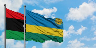 Libya ve Ruanda bayrağı birlikte beyaz bulutlu mavi gökyüzüne karşı rüzgarsal sallayarak. Diplomasi kavramı, uluslararası ilişkiler.