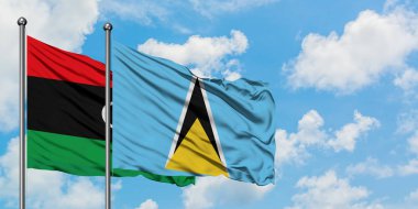 Libya ve Saint Lucia bayrağı birlikte beyaz bulutlu mavi gökyüzüne karşı rüzgarda sallayarak. Diplomasi kavramı, uluslararası ilişkiler.