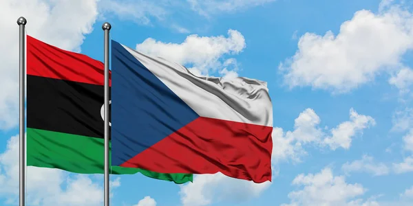Bandera de Libia y República Checa ondeando en el viento contra el cielo azul nublado blanco juntos. Concepto diplomático, relaciones internacionales . — Foto de Stock