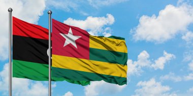 Libya ve Togo bayrağı birlikte beyaz bulutlu mavi gökyüzüne karşı rüzgarsal sallayarak. Diplomasi kavramı, uluslararası ilişkiler.