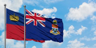 Liechtenstein ve Cayman Adaları bayrağı birlikte beyaz bulutlu mavi gökyüzüne karşı rüzgarda sallayarak. Diplomasi kavramı, uluslararası ilişkiler.