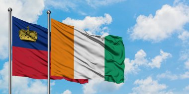 Liechtenstein ve Fildişi Sahili bayrağı birlikte beyaz bulutlu mavi gökyüzüne karşı rüzgarda sallayarak. Diplomasi kavramı, uluslararası ilişkiler.