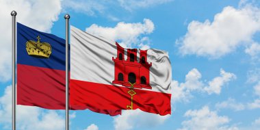 Lihtenştayn ve Cebelitarık bayrağı birlikte beyaz bulutlu mavi gökyüzüne karşı rüzgarda sallayarak. Diplomasi kavramı, uluslararası ilişkiler.