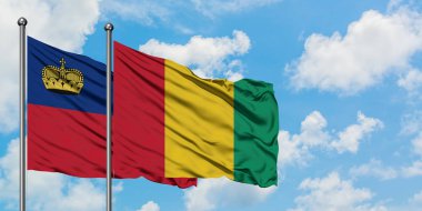 Liechtenstein ve Gine bayrağı birlikte beyaz bulutlu mavi gökyüzüne karşı rüzgarda sallayarak. Diplomasi kavramı, uluslararası ilişkiler.