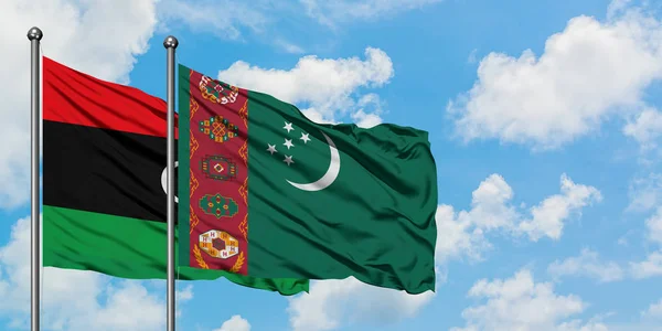 Bandera de Libia y Turkmenistán ondeando en el viento contra el cielo azul nublado blanco juntos. Concepto diplomático, relaciones internacionales . — Foto de Stock