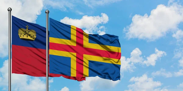 Liechtenstein and Aland Islands flag waving in the wind against white cloudy blue sky together. Diplomacy concept, international relations. — Stock Photo, Image