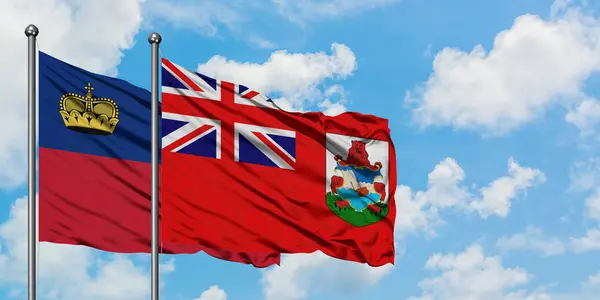 Bandera de Liechtenstein y Bermudas ondeando en el viento contra el cielo azul nublado blanco juntos. Concepto diplomático, relaciones internacionales . —  Fotos de Stock