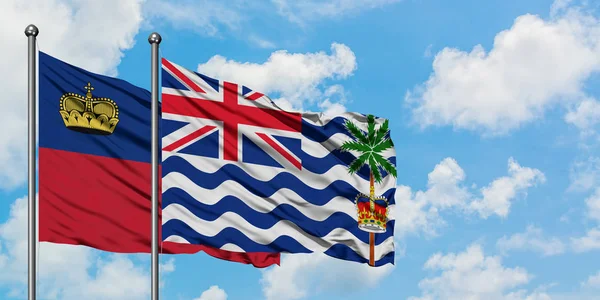 Bandera de Liechtenstein y del Territorio Británico del Océano Índico ondeando en el viento contra el cielo azul nublado blanco juntos. Concepto diplomático, relaciones internacionales . — Foto de Stock