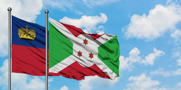 Bandera de Liechtenstein y Burundi ondeando en el viento contra el cielo azul nublado blanco juntos. Concepto diplomático, relaciones internacionales . — Foto de Stock