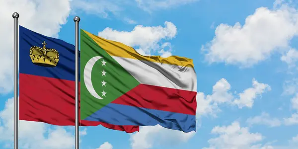 Bandera de Liechtenstein y Comoras ondeando en el viento contra el cielo azul nublado blanco juntos. Concepto diplomático, relaciones internacionales . — Foto de Stock