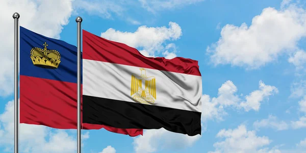 Bandera de Liechtenstein y Egipto ondeando en el viento contra el cielo azul nublado blanco juntos. Concepto diplomático, relaciones internacionales . — Foto de Stock