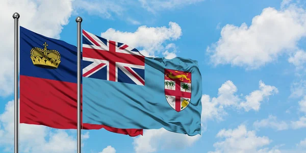 Bandera de Liechtenstein y Fiyi ondeando en el viento contra el cielo azul nublado blanco juntos. Concepto diplomático, relaciones internacionales . — Foto de Stock