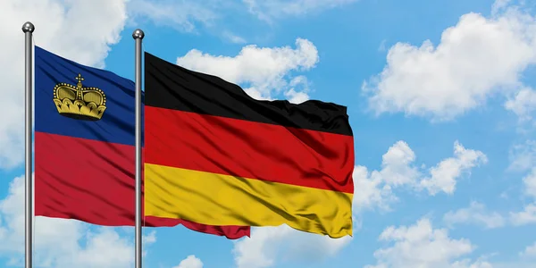 Liechtenstein e Germania sventolano bandiera nel vento contro bianco cielo blu nuvoloso insieme. Concetto di diplomazia, relazioni internazionali . — Foto Stock