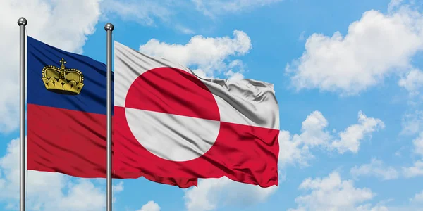 Drapeau du Liechtenstein et du Groenland agitant dans le vent contre ciel bleu nuageux blanc ensemble. Concept de diplomatie, relations internationales . — Photo