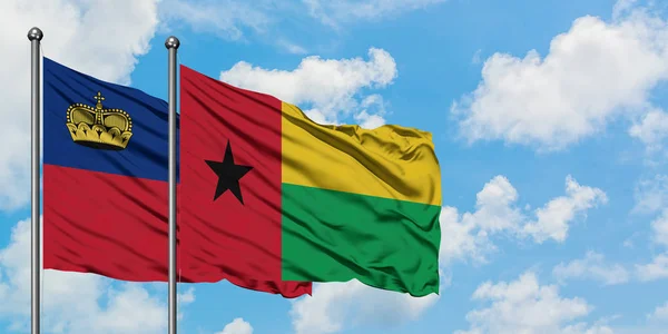 Bandera de Liechtenstein y Guinea Bissau ondeando en el viento contra el cielo azul nublado blanco juntos. Concepto diplomático, relaciones internacionales . — Foto de Stock