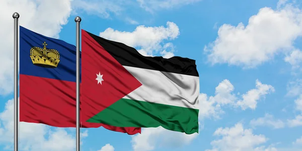 Bandera de Liechtenstein y Jordania ondeando en el viento contra el cielo azul nublado blanco juntos. Concepto diplomático, relaciones internacionales . — Foto de Stock