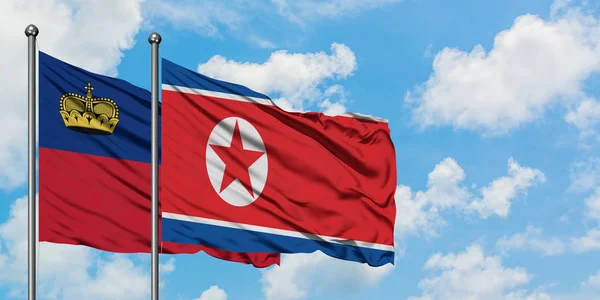 Liechtenstein e a bandeira da Coreia do Norte agitando no vento contra o céu azul nublado branco juntos. Conceito de diplomacia, relações internacionais . — Fotografia de Stock