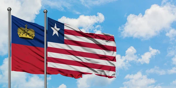 Liechtenstein i Liberia flagi machając w wiatr przed białym zachmurzone błękitne niebo razem. Koncepcja dyplomacji, stosunki międzynarodowe. — Zdjęcie stockowe
