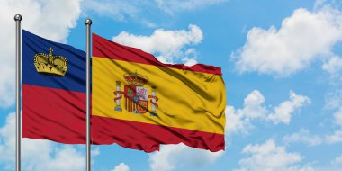 Liechtenstein ve İspanya bayrağı birlikte beyaz bulutlu mavi gökyüzüne karşı rüzgarda sallayarak. Diplomasi kavramı, uluslararası ilişkiler.