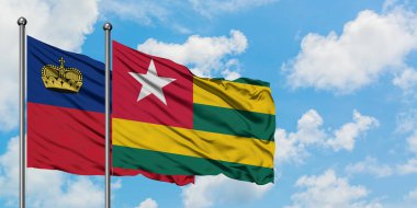 Liechtenstein ve Togo bayrağı birlikte beyaz bulutlu mavi gökyüzüne karşı rüzgarda sallayarak. Diplomasi kavramı, uluslararası ilişkiler.