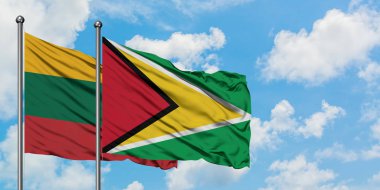 Litvanya ve Guyana bayrağı birlikte beyaz bulutlu mavi gökyüzüne karşı rüzgarda sallayarak. Diplomasi kavramı, uluslararası ilişkiler.