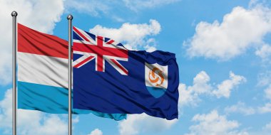 Lüksemburg ve Anguilla bayrağı birlikte beyaz bulutlu mavi gökyüzüne karşı rüzgarda sallayarak. Diplomasi kavramı, uluslararası ilişkiler.